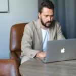 Professional executive researching LinkedIn profile on laptop